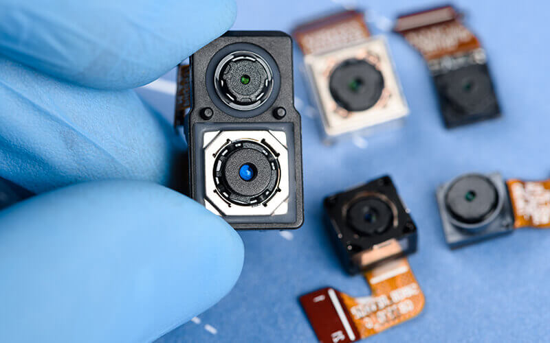 A gloved hand displaying a compact camera alongside several other cameras