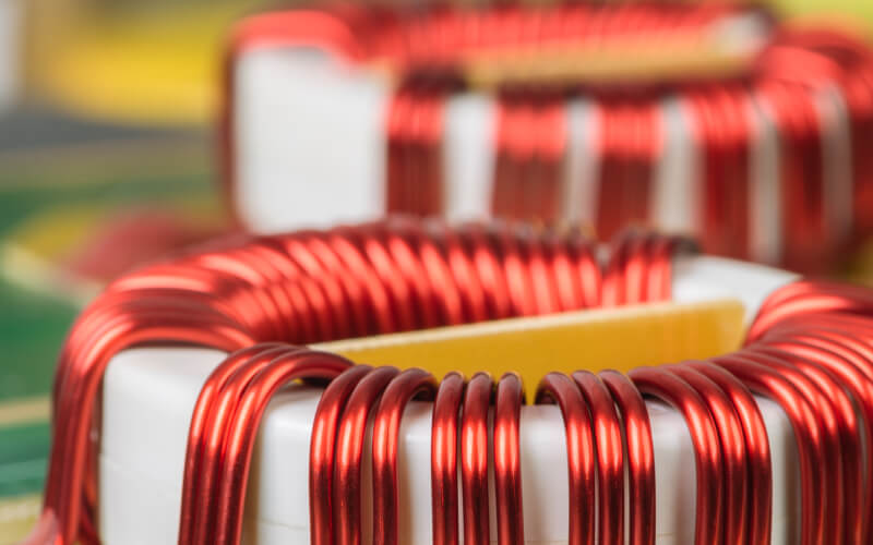 Inductors with red copper wire tightly wound around a white ring-shaped core